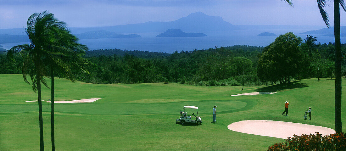 Menschen auf dem Golfplatz des Tagaytay Country Club mit Blick auf Vulkan Taal, Tagaytay, Luzon Island , Philippinen, Asien