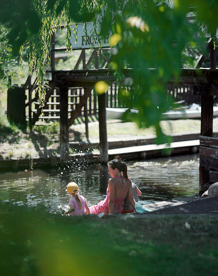 Mother and children sitting at jetty, Leipe, Spreewald, Brandenburg, Germany