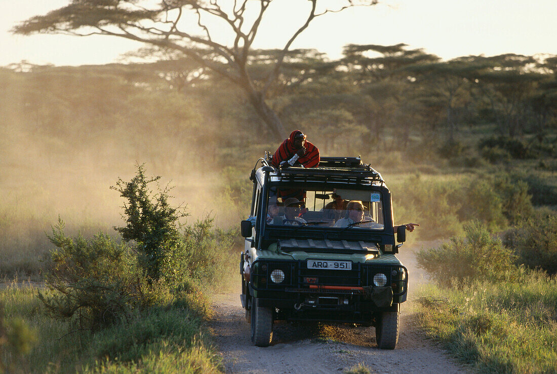 Tourists on a safari with massai tour guide, Serengeti, Tansania, East Africa