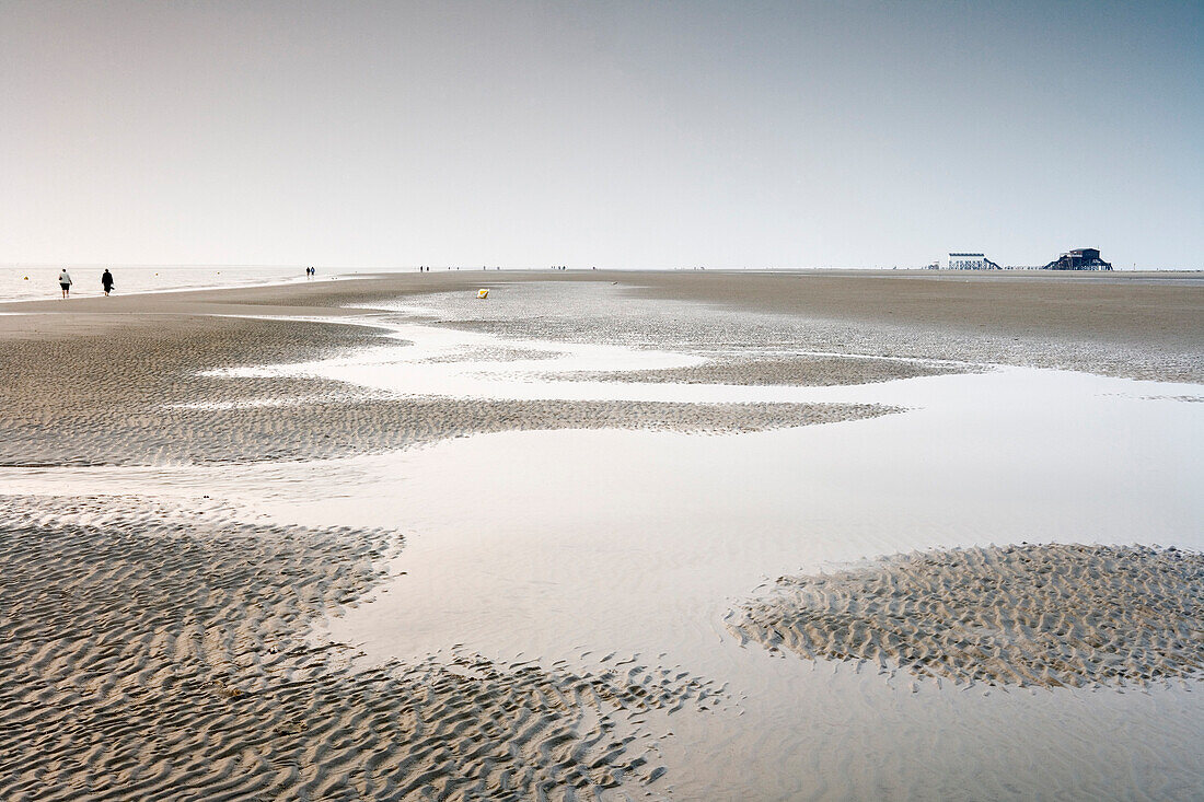 Persons walking through tideland, St. Peter-Ording, Schleswig-Holstein, Germany