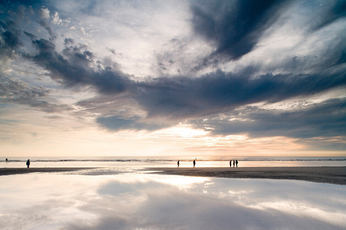 Persons walking through tideland, St. Peter-Ording, Schleswig-Holstein, Germany