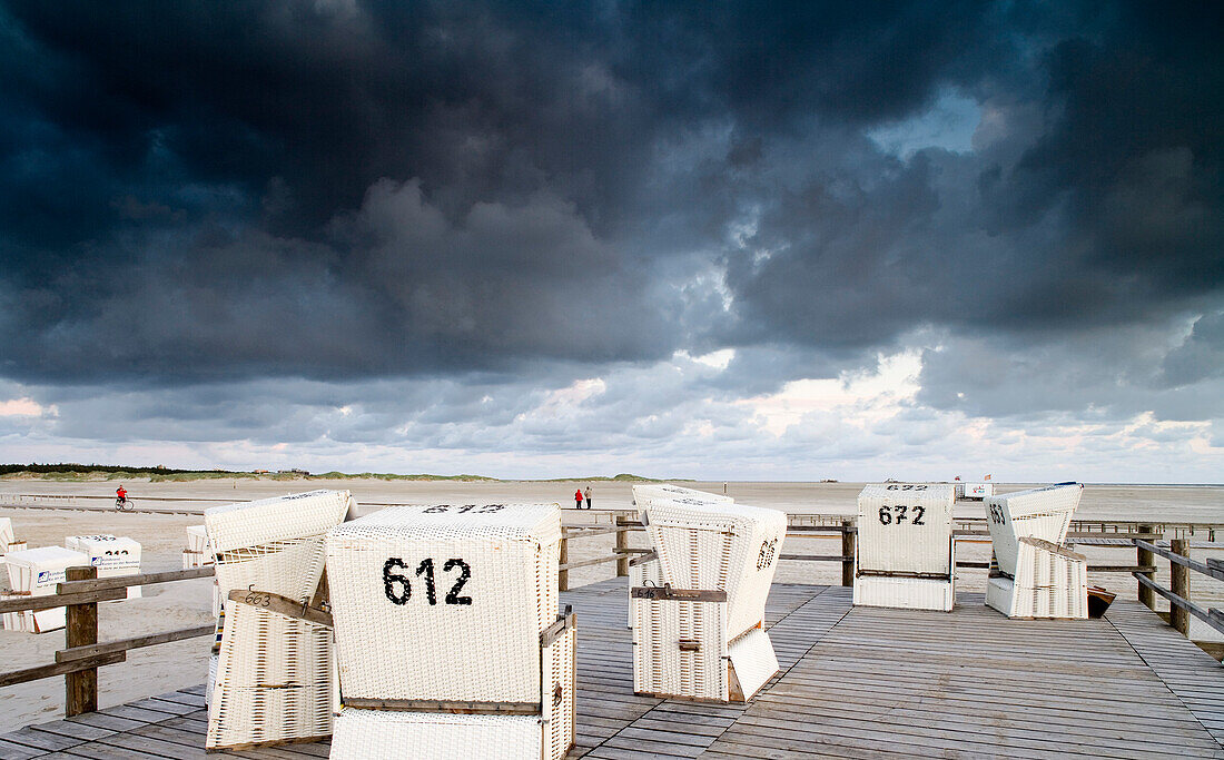 Strandkörbe am Strand unter dunklen Wolken, St. Peter Ording, Halbinsel Eiderstedt, Schleswig-Holstein, Deutschland, Europa