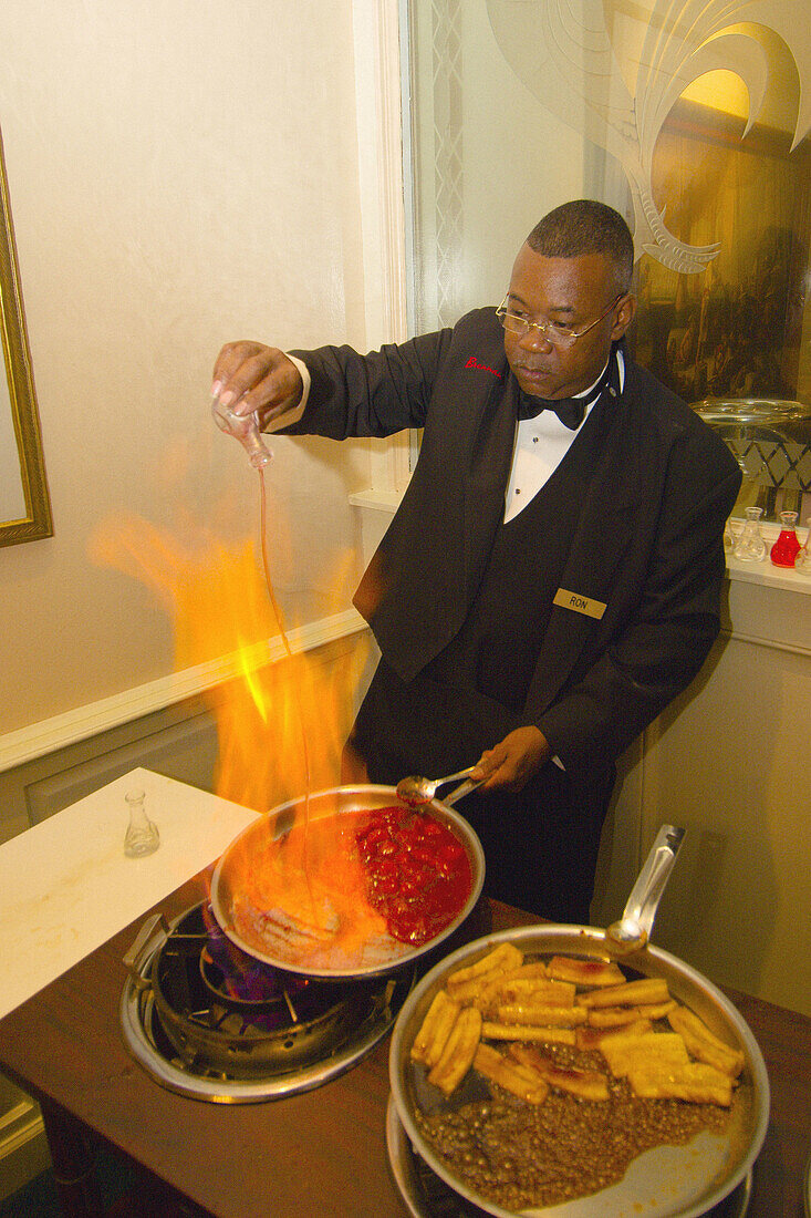 Waiter flambeing desserts (Crepes Fitzgerald on left and Bananas Foster on right), Brennans Restaurant in the French Quarter, New Orleans, Louisiana, USA