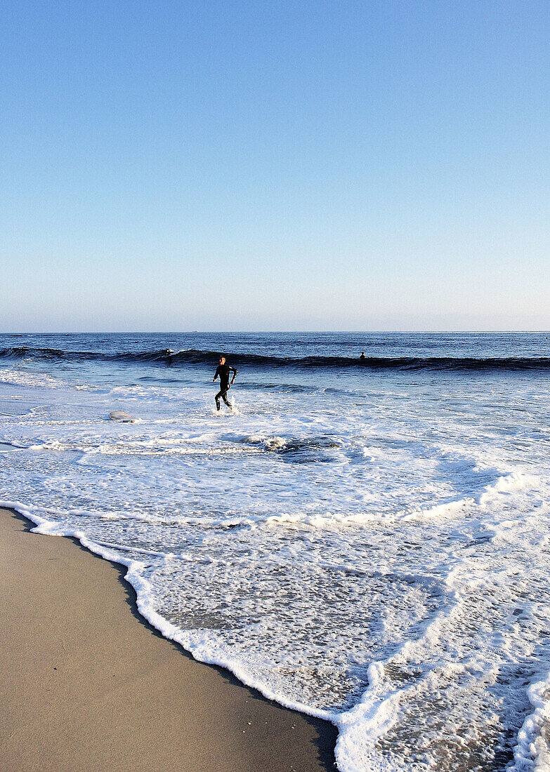 Surfer getting out of the water. Pacific Ocean. Baja California. Mexico.