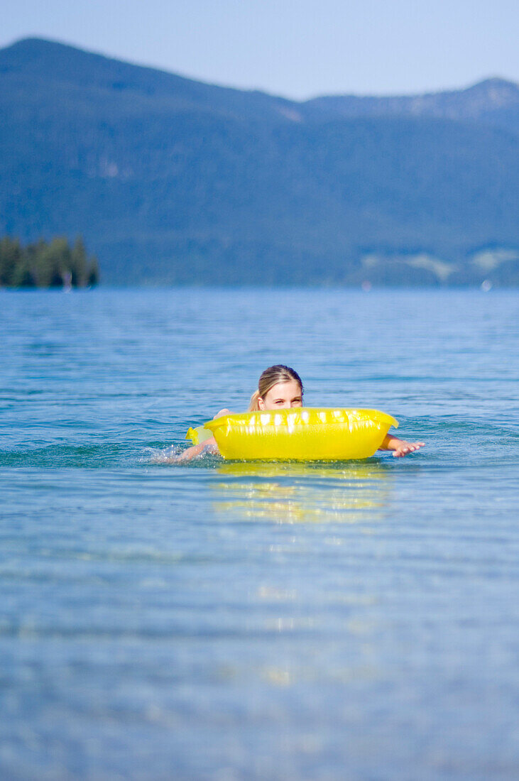 One young woman, girl, lying on an air mattress on the lake, Lake Walchensee, Upper Bavaria, Bavaria, Germany