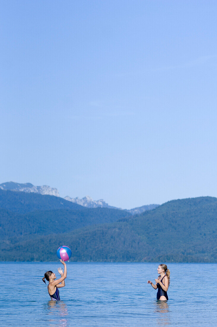 Two young women playing with a ball in Lake Walchensee, Upper Bavaria, Bavaria, Germany