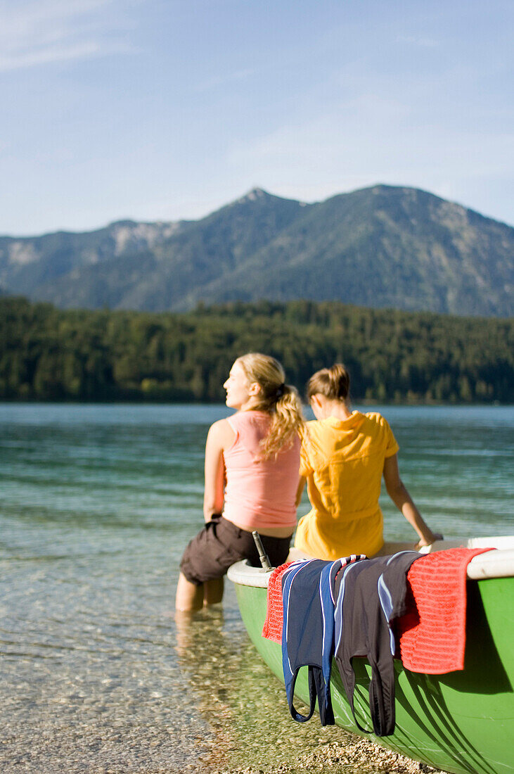 Two young women sitting on a boat at lake Walchensee, Bavaria, Germany