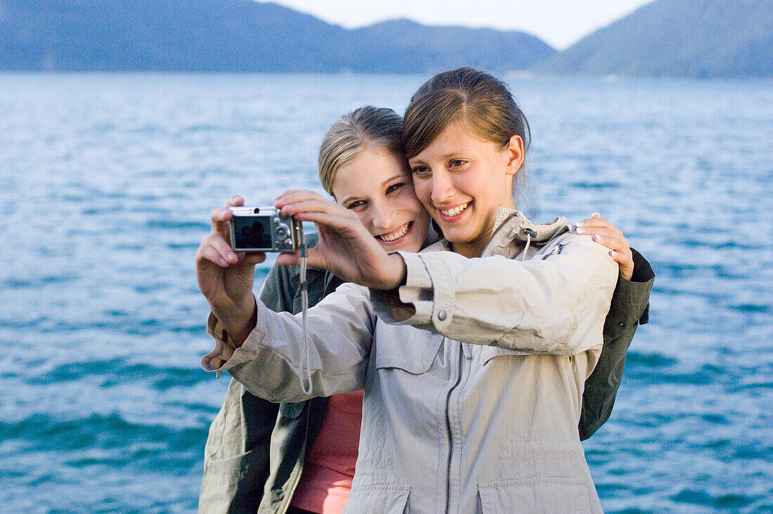 Two young women, girls, taking a photograph of themselves, Lake Walchensee, Upper Bavaria, Bavaria, Germany