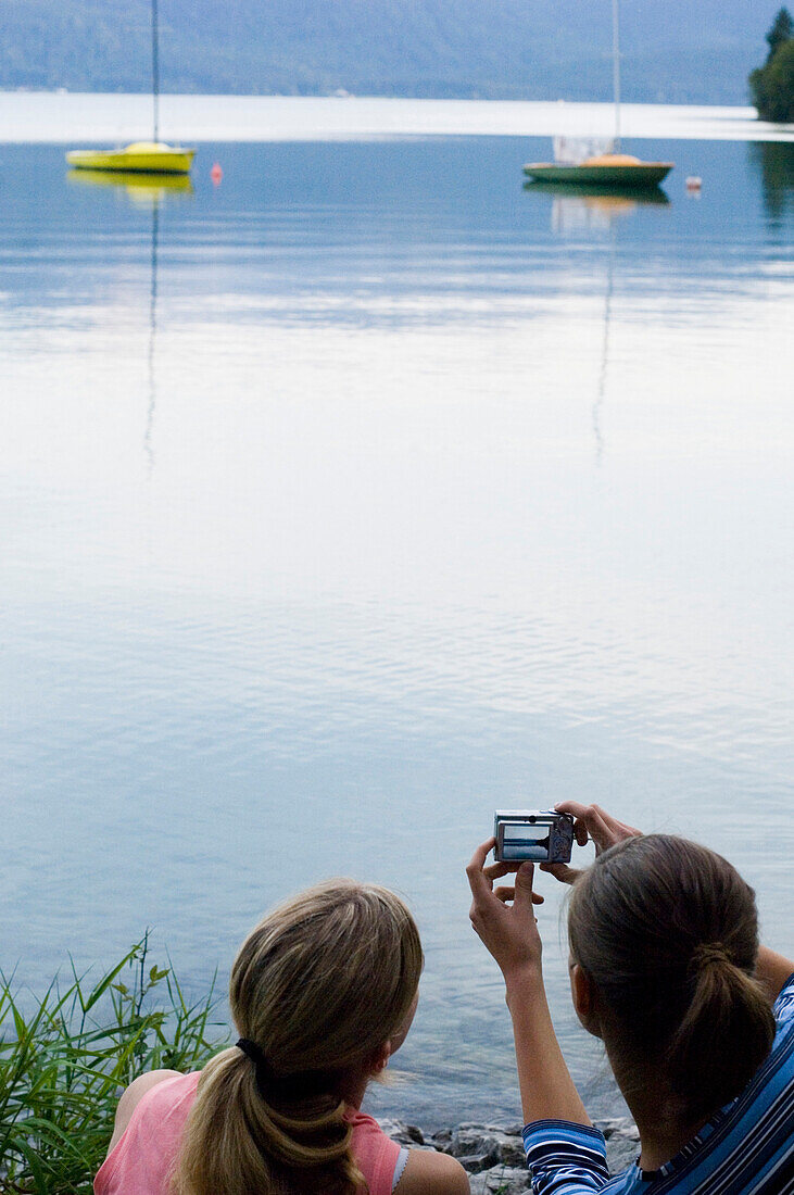 Two young women taking a photo of lake Walchensee, Bavaria, Germany