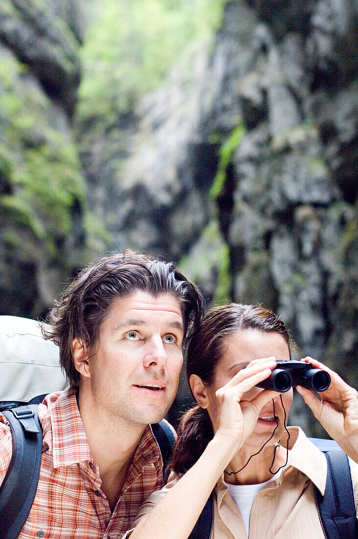 Couple hiking in the Partnachklamm, Woman looking through binoculars, Garmisch-Partenkirchen, Bavaria, Germany