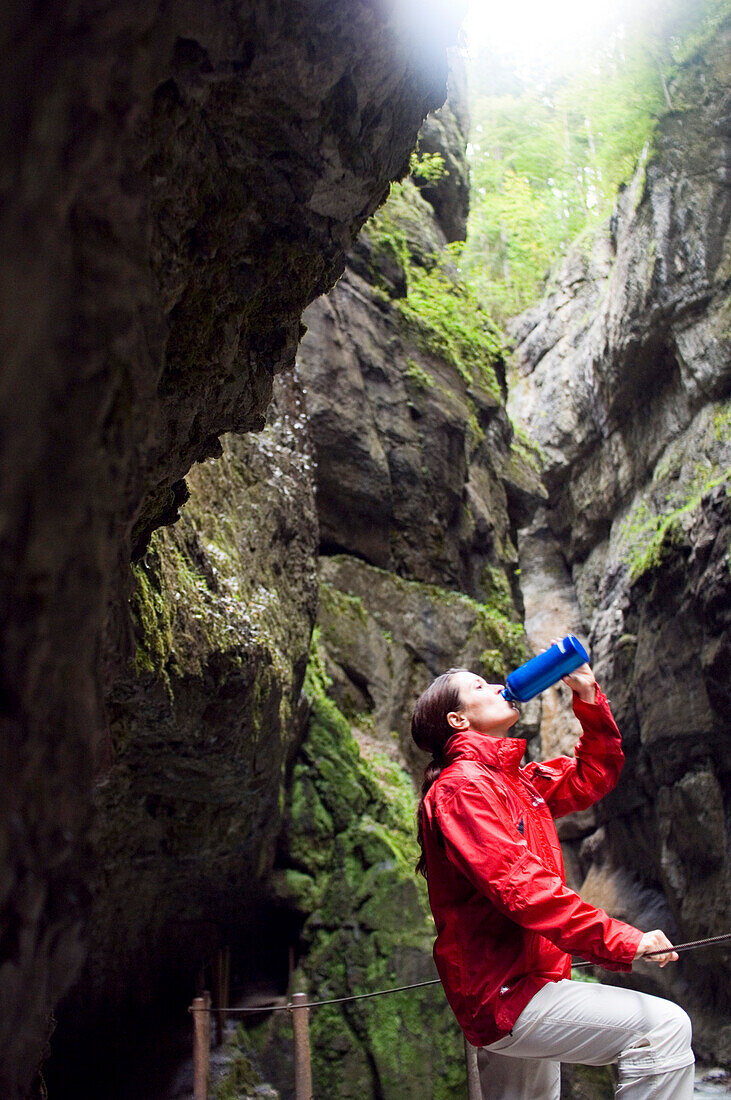 Frau beim Wandern, Frau macht Pause und trinkt, Partnachklamm, Garmisch-Partenkirchen, Bayern, Deutschland
