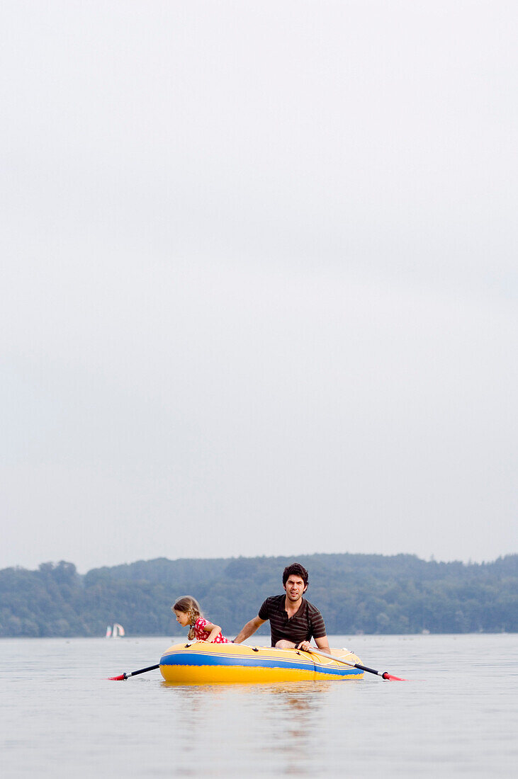 Vater und Tochter (4-5 Jahre) in einem Gummiboot auf dem Ammersee, Bayern, Deutschland