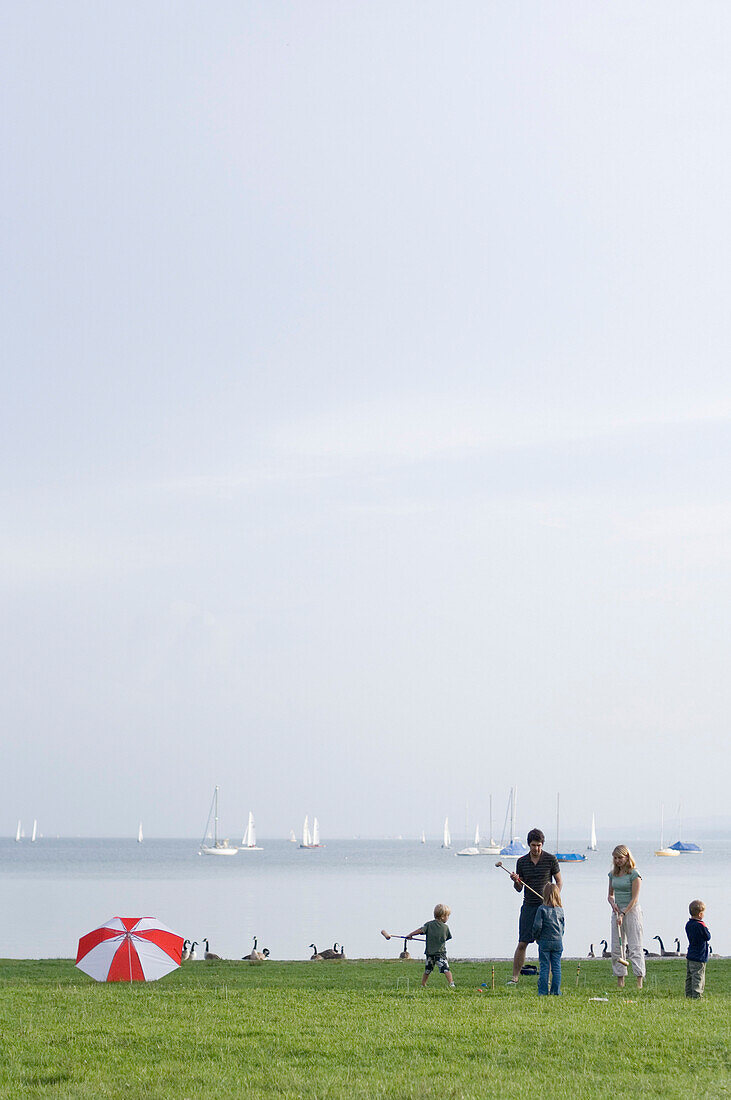 Family playing croquet on the shore of lake Ammersee, Upper Bavaria, Bavaria, Germany