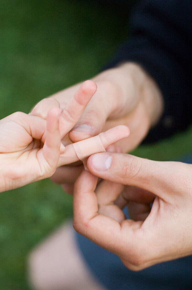 Man putting plaster on child's finger