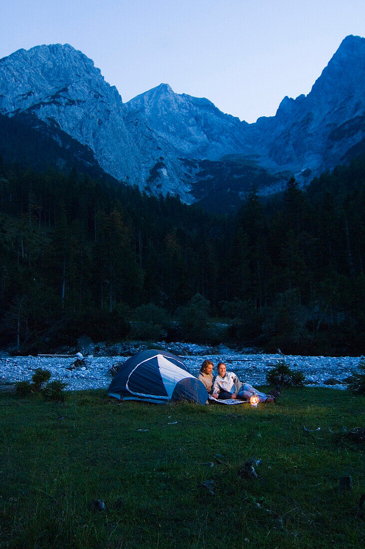 Young couple sitting near a tent, Lenggries, Upper Bavaria, Bavaria, Germany