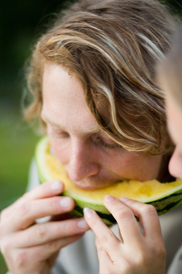 Junger Mann und Frau teilen sich eine Melone, Paar, Oberbayern, Bayern, Deutschland
