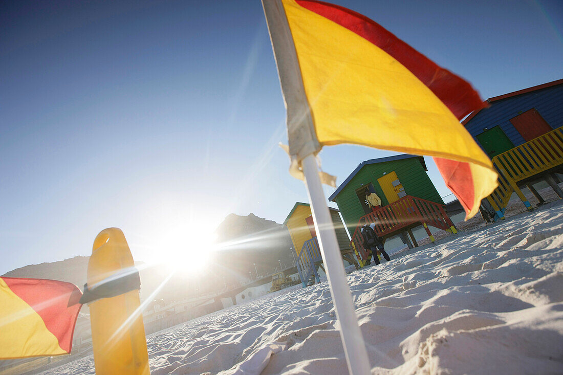 Beach huts and flag on the beach at Muizenberg, Cape Town, Western Cape, South Africa