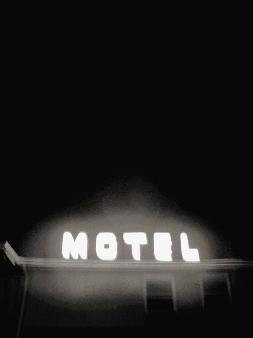 The glowing neon sign for an inexpensive motel is captured in Black and White at night.