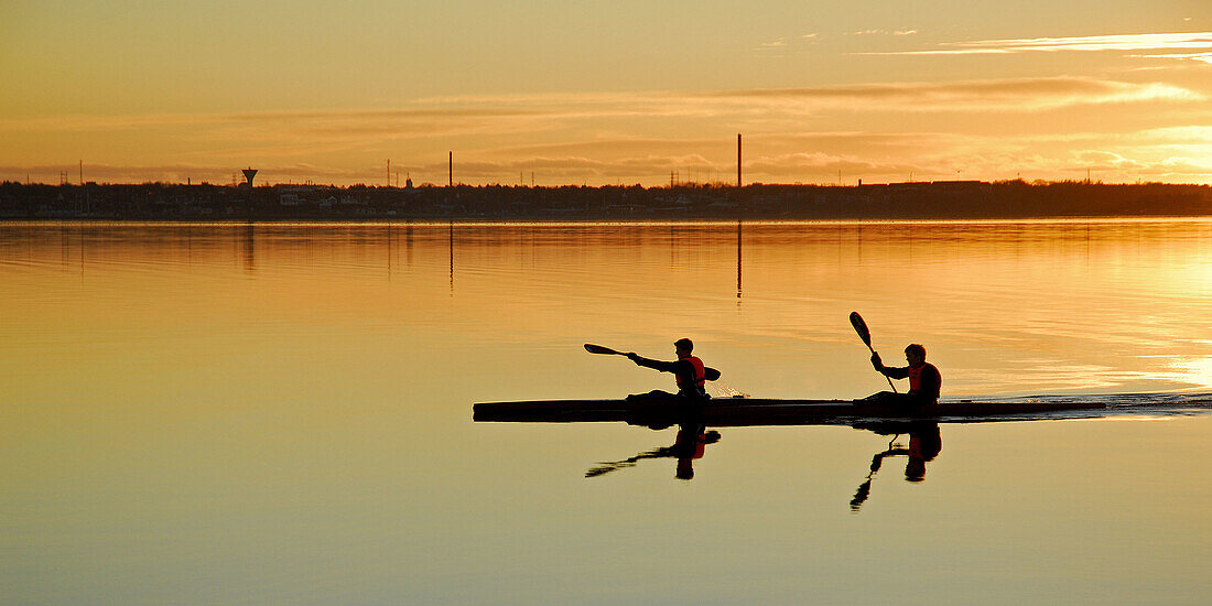 Two paddelers kayaking on Struer bay, Limfjorden, western Jutland, Denmark. Sunset and golden colors.