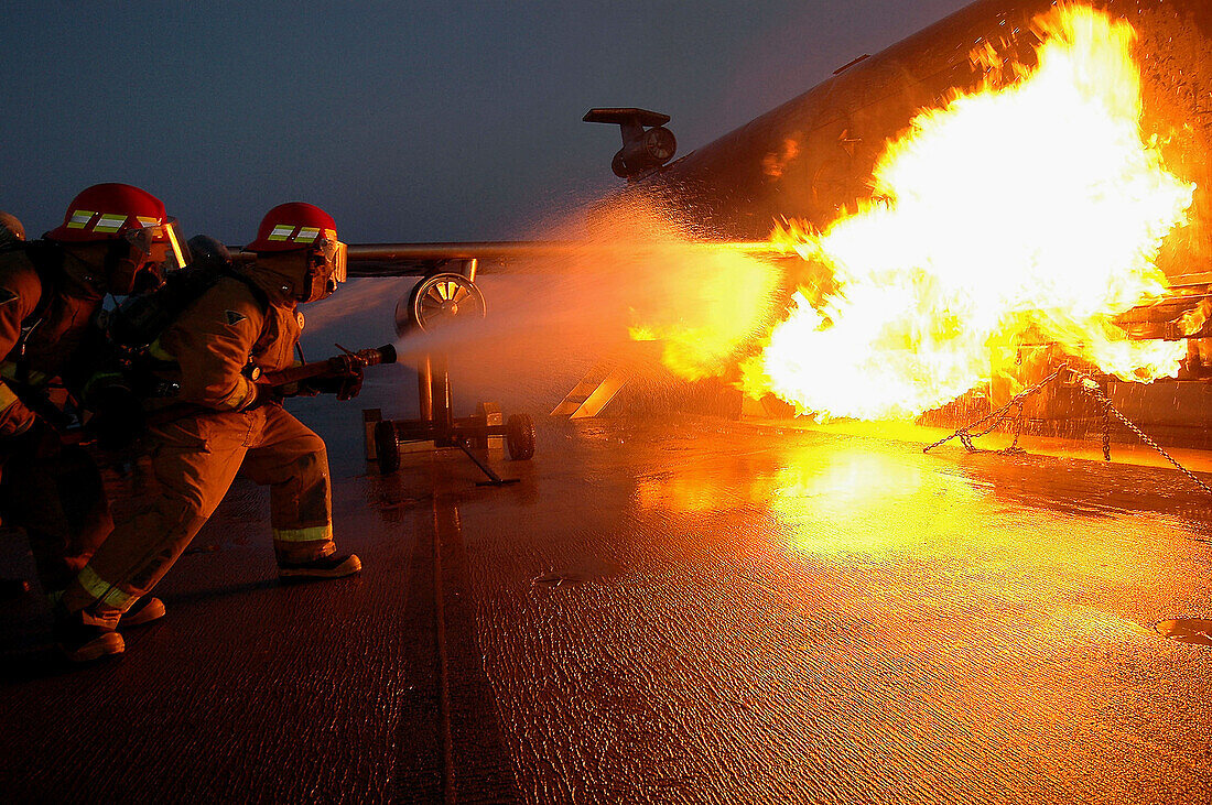 Hose team assigned to a ships repair locker combats a controlled fire on the Mobile Aircraft Firefighting Training Device (MAFTD) aboard aboard the conventionally powered aircraft carrier USS John F. Kennedy (CV 67)