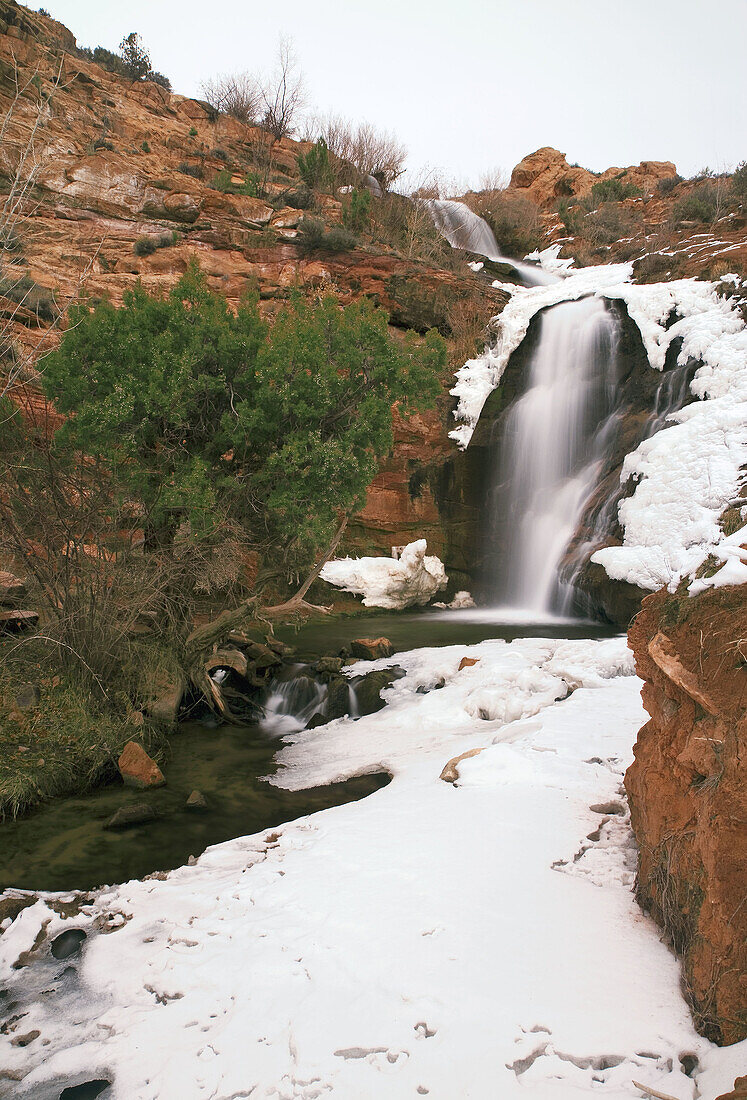 Snow and ice surrounds Faux Falls on a cold winter day, Moab, Utah, USA.