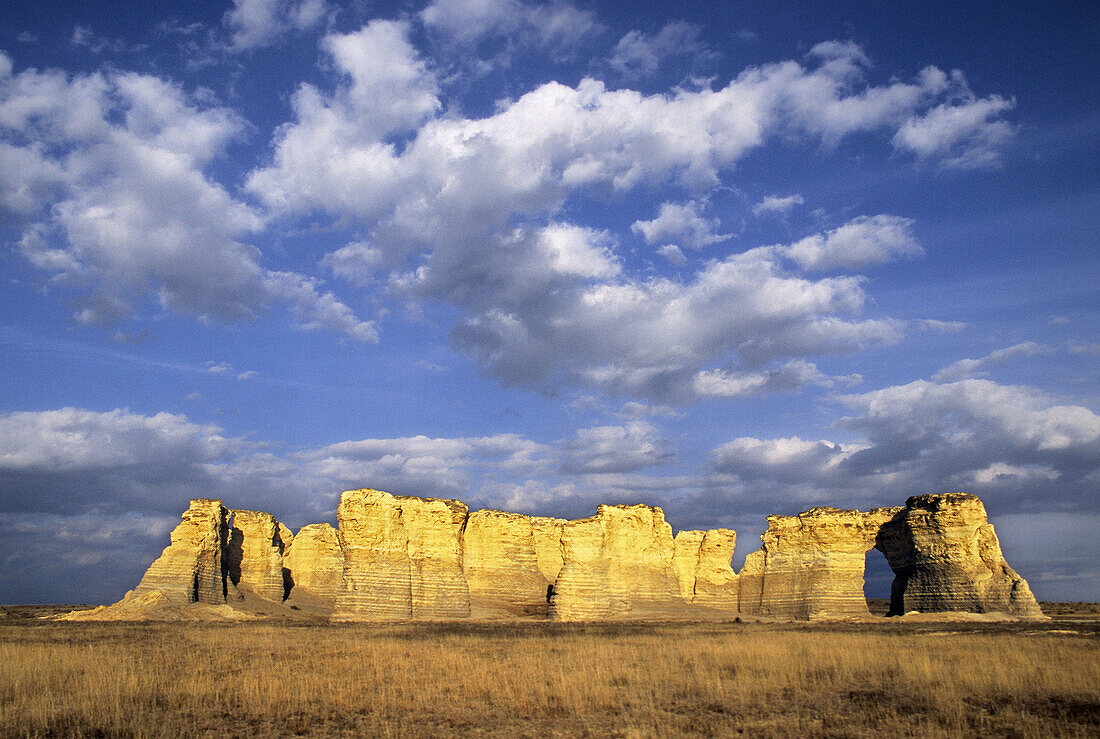 Once buried beneath an ancient sea, Monument Rocks rises from the plains below a sky filled with cottonball clouds, Kansas, USA.