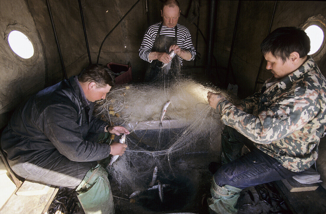 Fishermen inside fishing tent over ice hole on Baikal lake in winter, Siberia, Russia