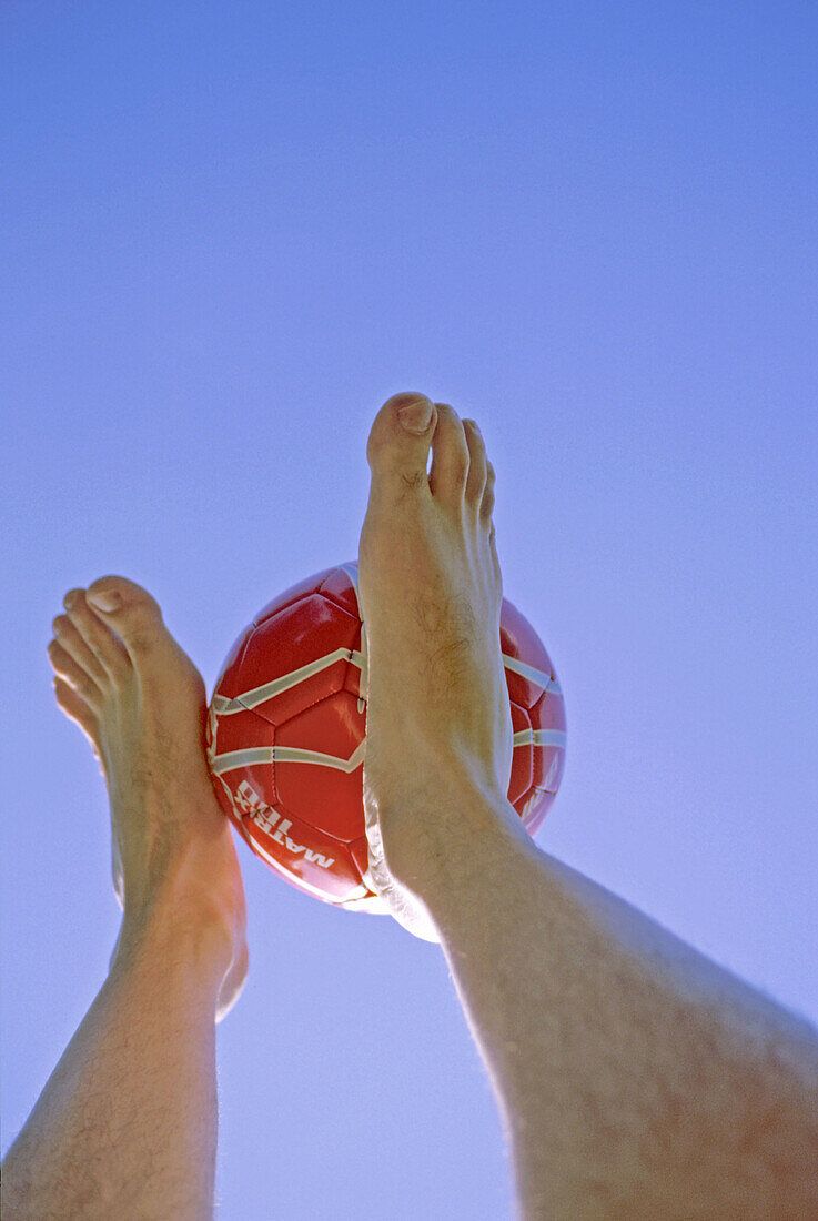 34 year old Latino-American man with hairy legs holding and throwing a football (soccer ball) with his feet. New York City Central Park. Manhattan, United States