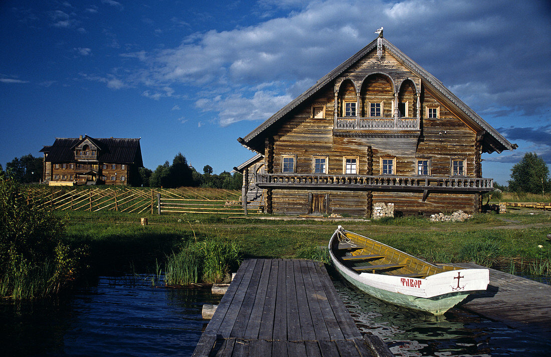 Traditional Russian wooden houses (early 191th- 20th century), pier and boat, Vasilevo. Kizhi island, Onega lake, Karelia, Russia