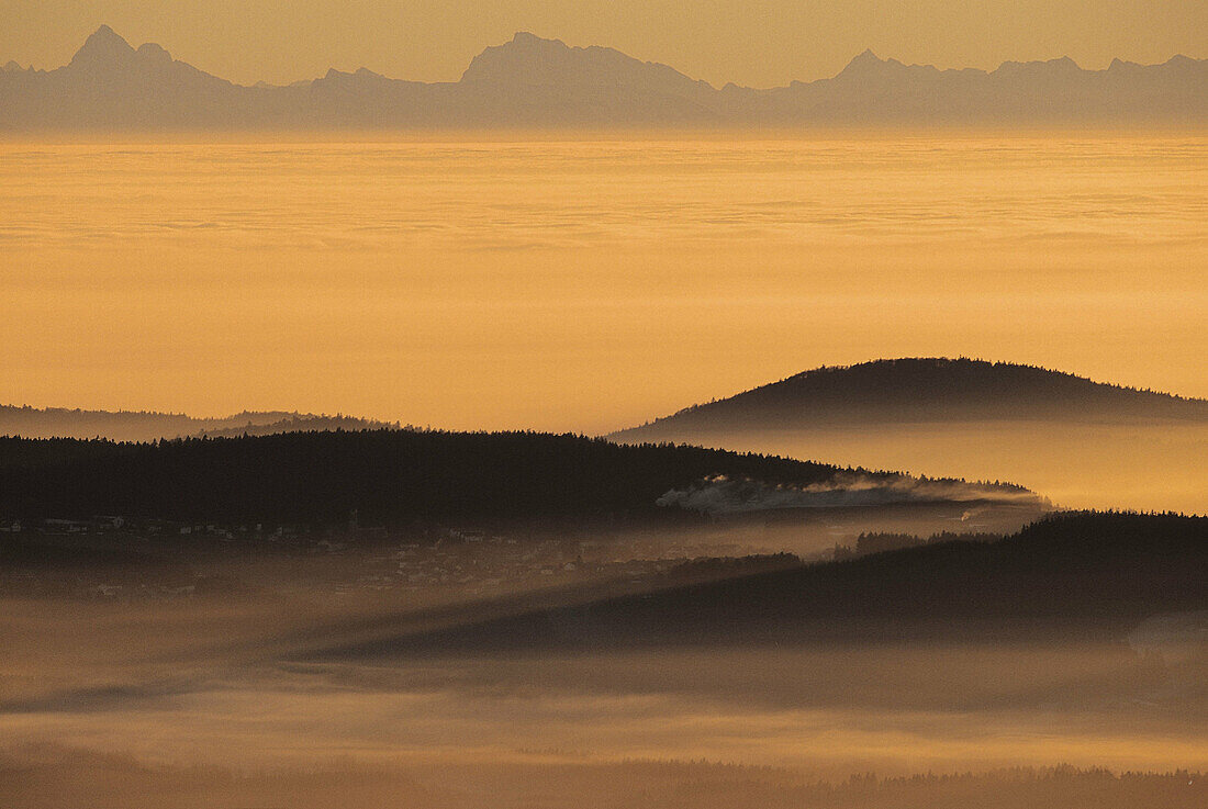 Mist in the valley near Grafenau in autumn looking from the low mountain range at the alpine chain, Bavarian Forest National Park. Germany