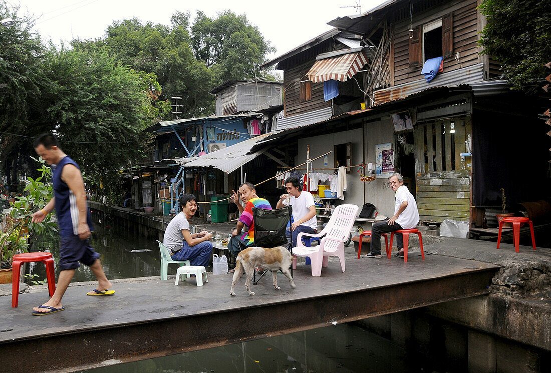 Einheimische auf einer Brücke über einem Klong im Phra Nathon Viertel, Bangkok, Thailand