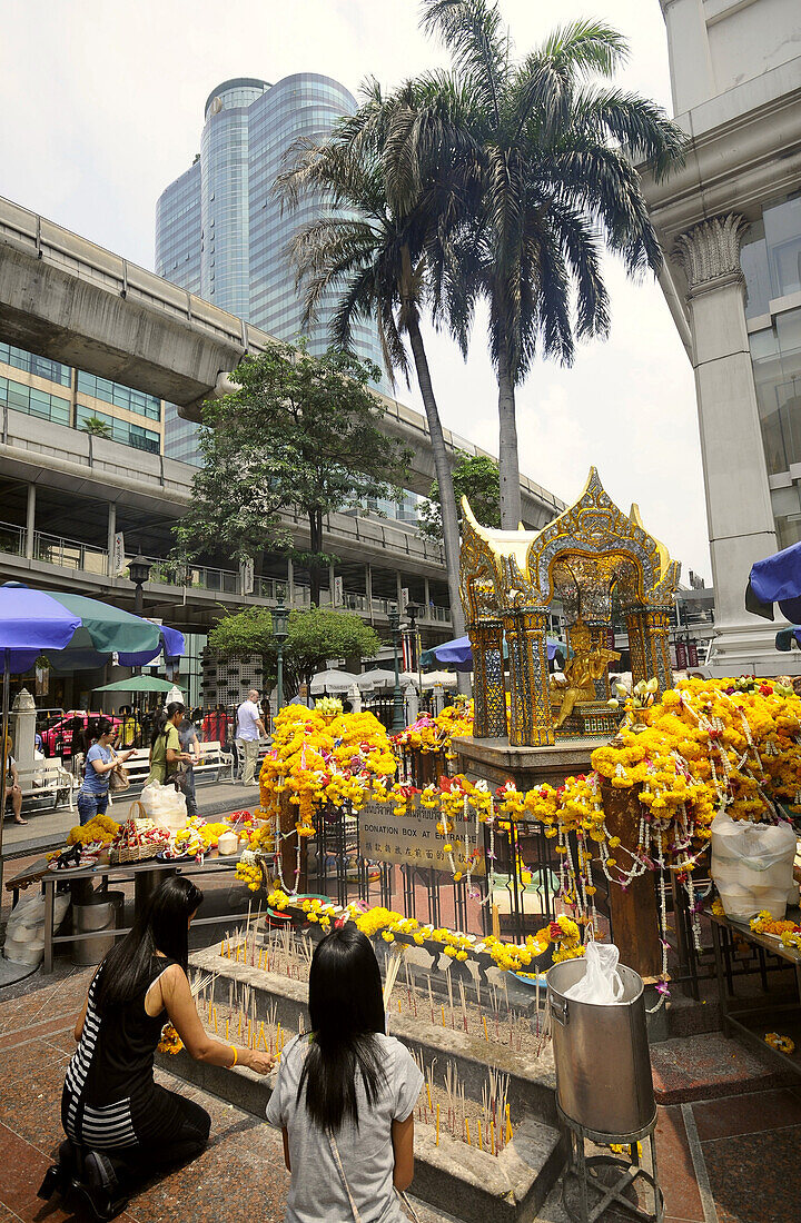Two female worshippers in front of the Erawan Shrine, Bangkok, Thailand
