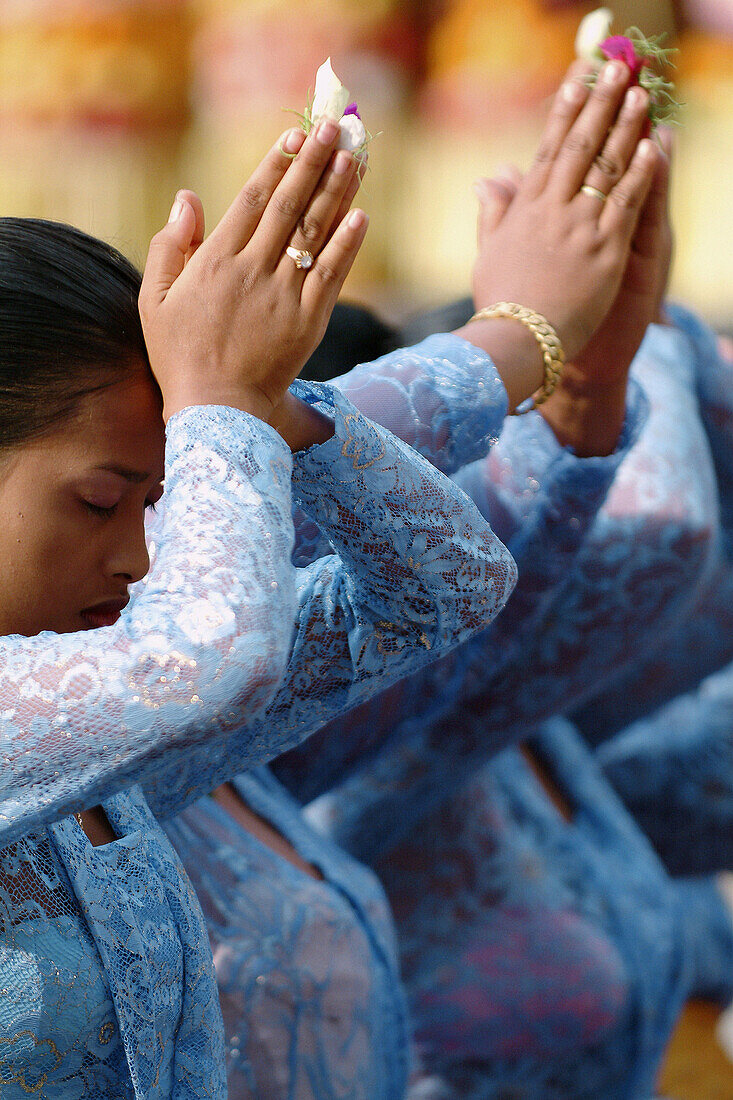 balinese woman in traditional attire praying in ceremony