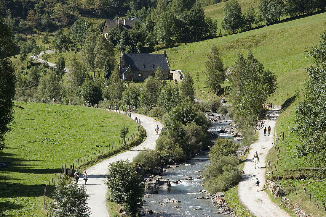 Hikers strolling next to a river. Pyrenees Mountains, France.