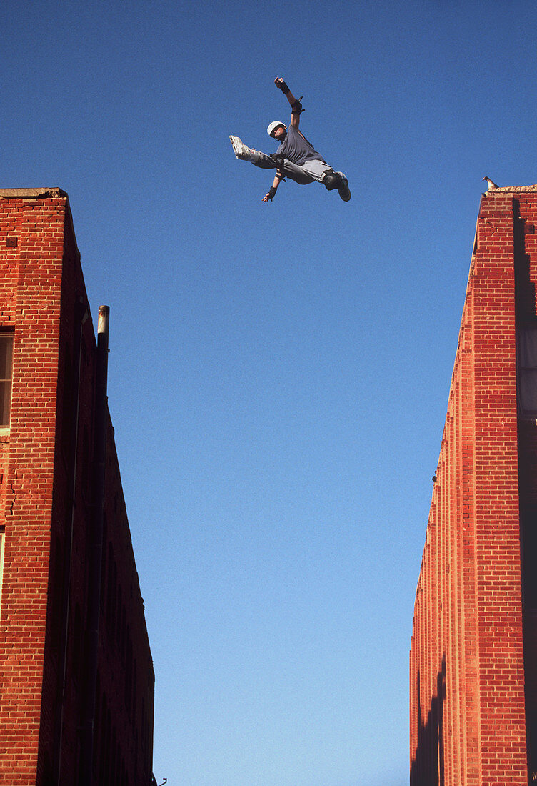 Inline skater jumps between two buildings.