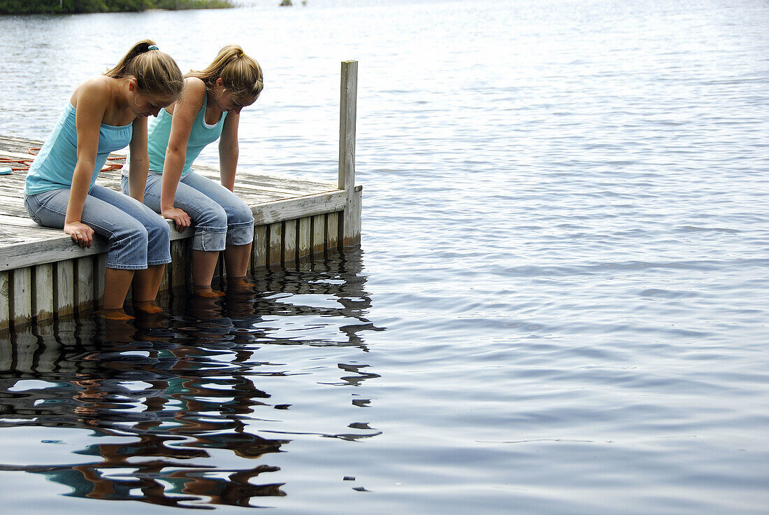 girl 13 girl 18 sitting on dock together looking at water