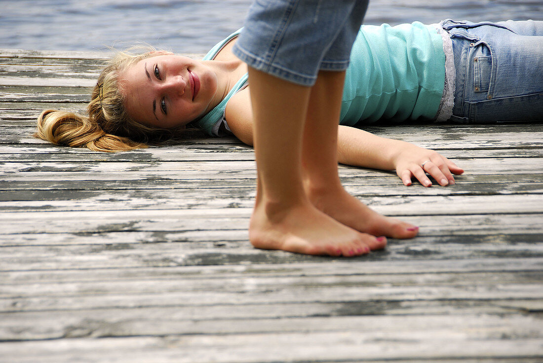 legs of girl 18 standing girl 13 laying on dock on lake