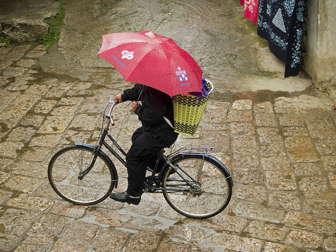 riding cobbled streets in the rain, Lijiang, China