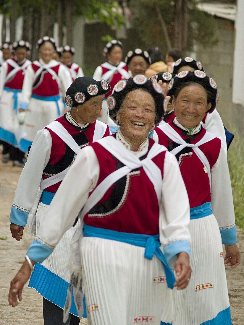 large group of Naxi women making their way through the streets of Lijiang, China