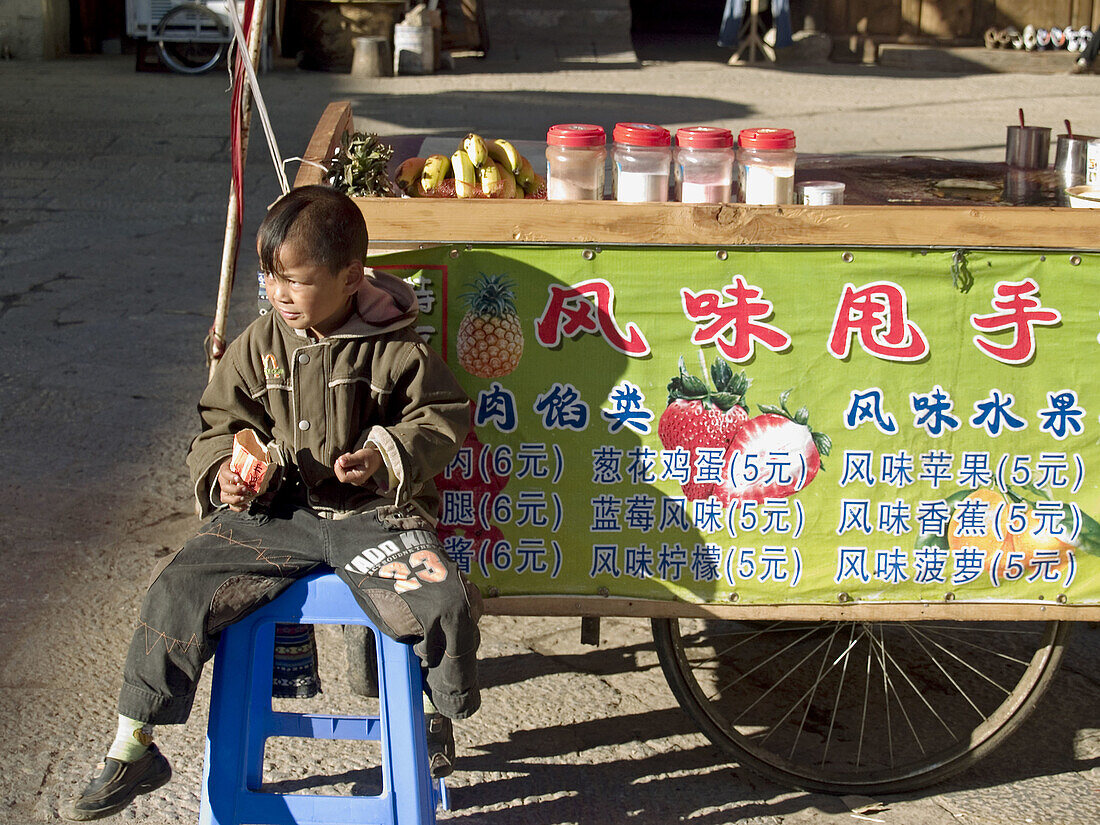 boy sits in front of fruit shake vendor, Shangri La, China