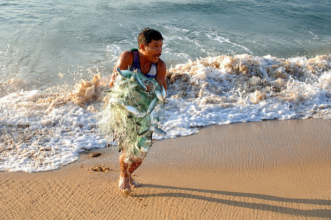 Fischer mit einem Netz voll Fische am Strand von Mazunte, Mexiko