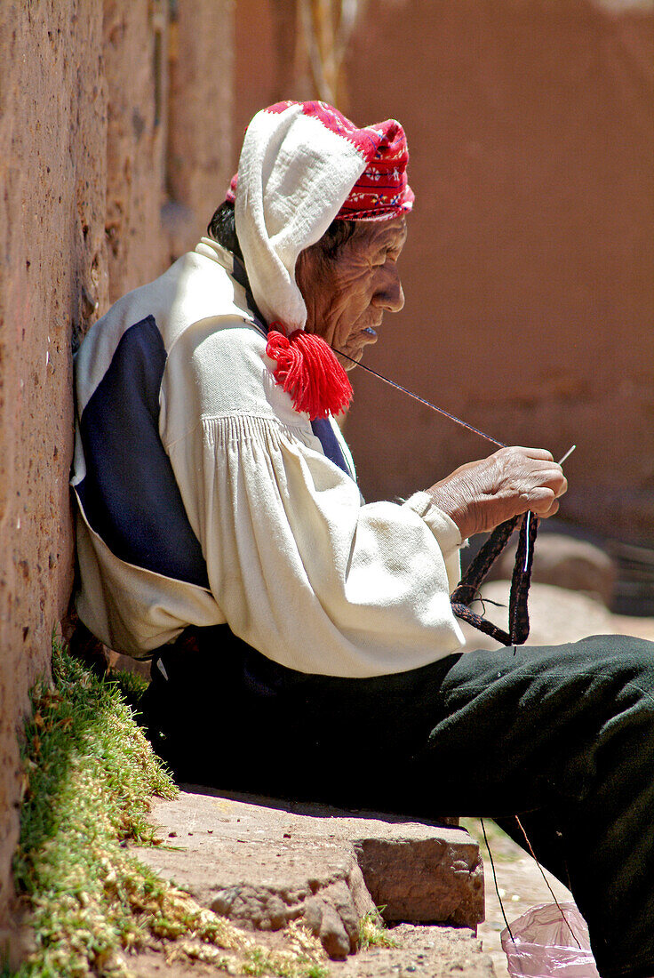 Indigenous man knitting on the island of Taquille, Lake Titicaca, Peru, South America