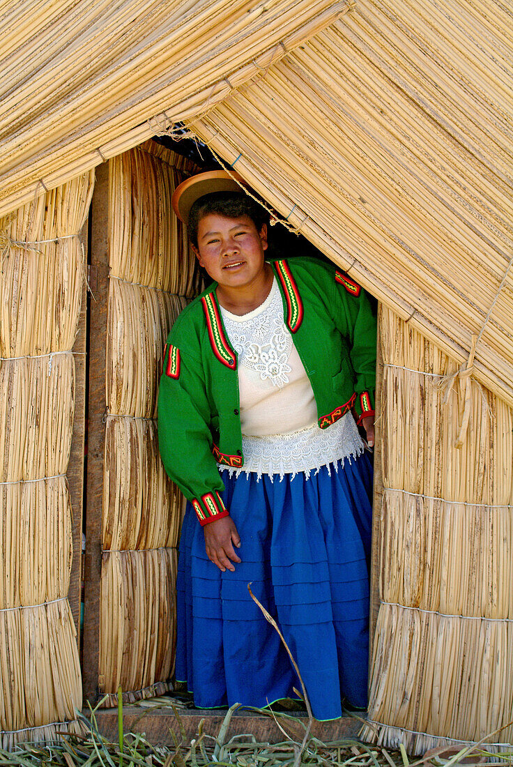 Indigenous woman of the Uros people in front of a reef hut, Lake Titicaca, Peru, South America