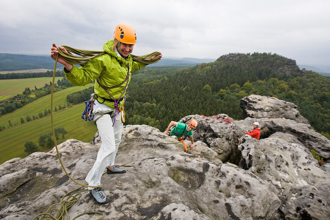 A young woman collects the rope on the summit of Papststein, Elbe Sandstone Mountains, Saxon Switzerland, Saxony, Germany