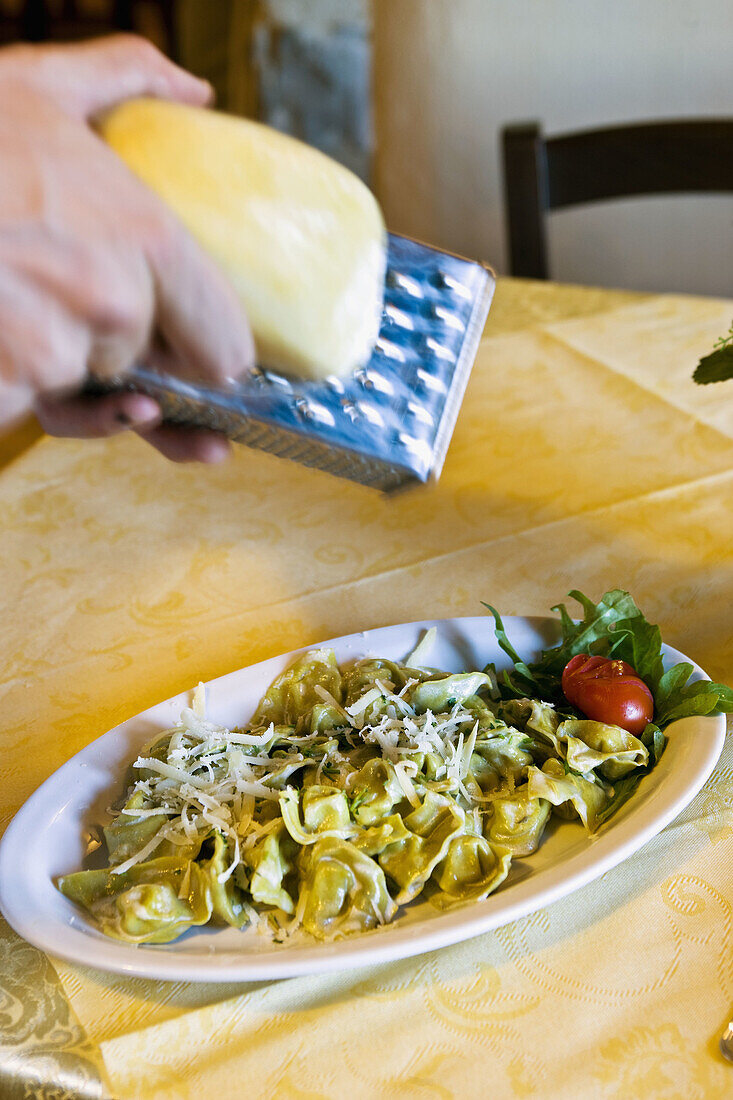 Il Casolare dei Baroni' restaurant, grating 'Formaggio di Fossa'on 'Tortelloni di Ricotta'. Doviola. Italy.