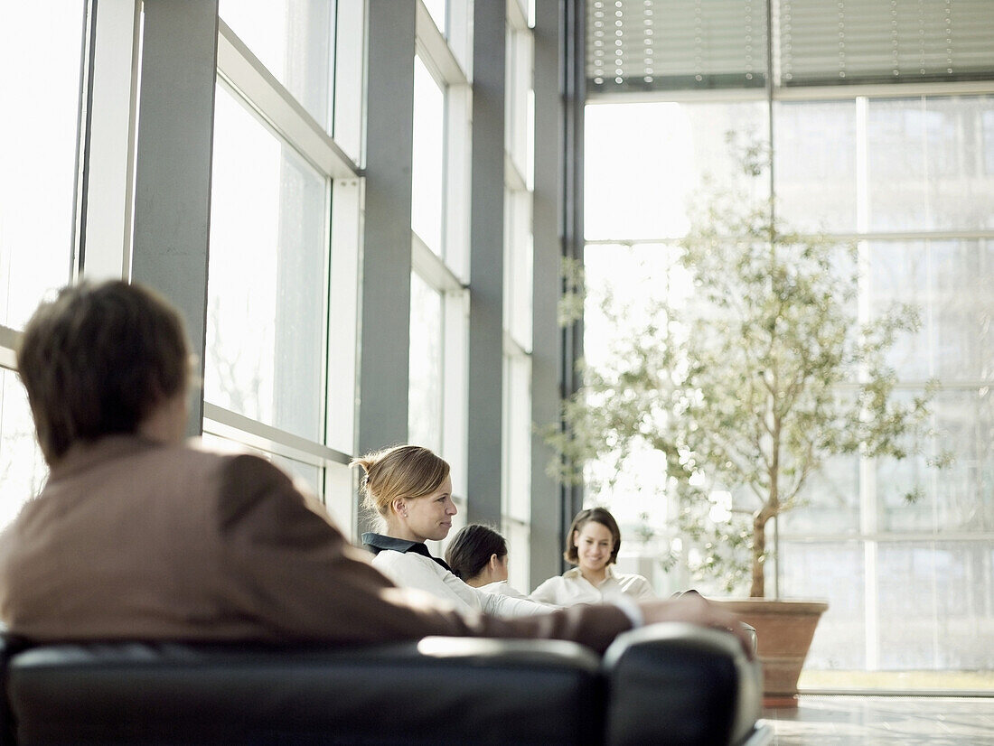 Geschäftsleute sitzen in einem Bürogebäude, München, Bayern, Deutschland