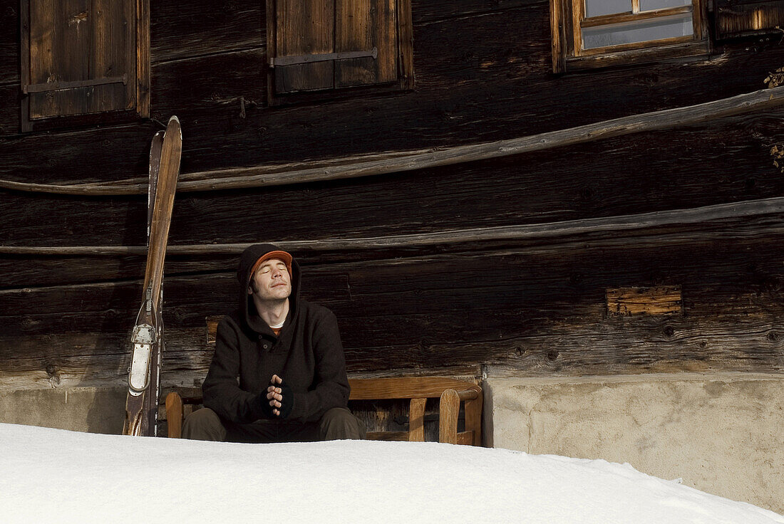 Mann sitzt mit geschlossenen Augen von einer Almhütte, Hirschegg, Vorarlberg, Österreich