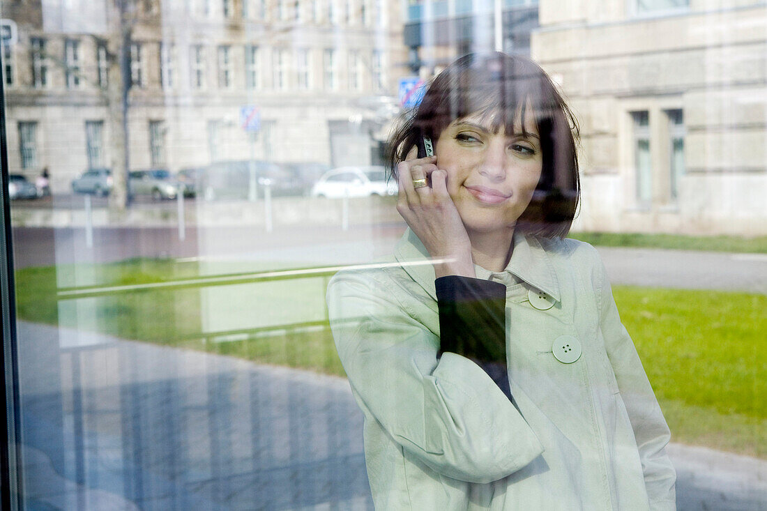 Young woman with mobile phone at a promenade, Duesseldorf, North Rhine-Westphalia, Germany