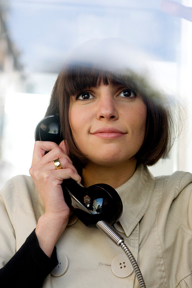 Junge Frau telefoniert in öffentlicher Telefonzelle, Düsseldorf, Nordrhein-Westfalen, Deutschland