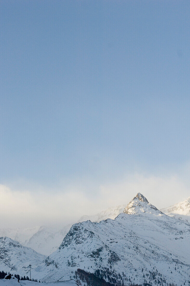 Schneebedeckte Bergspitzen in Wattewolken bei Sonnenuntergang, Schnalstal, Südtirol, Italien